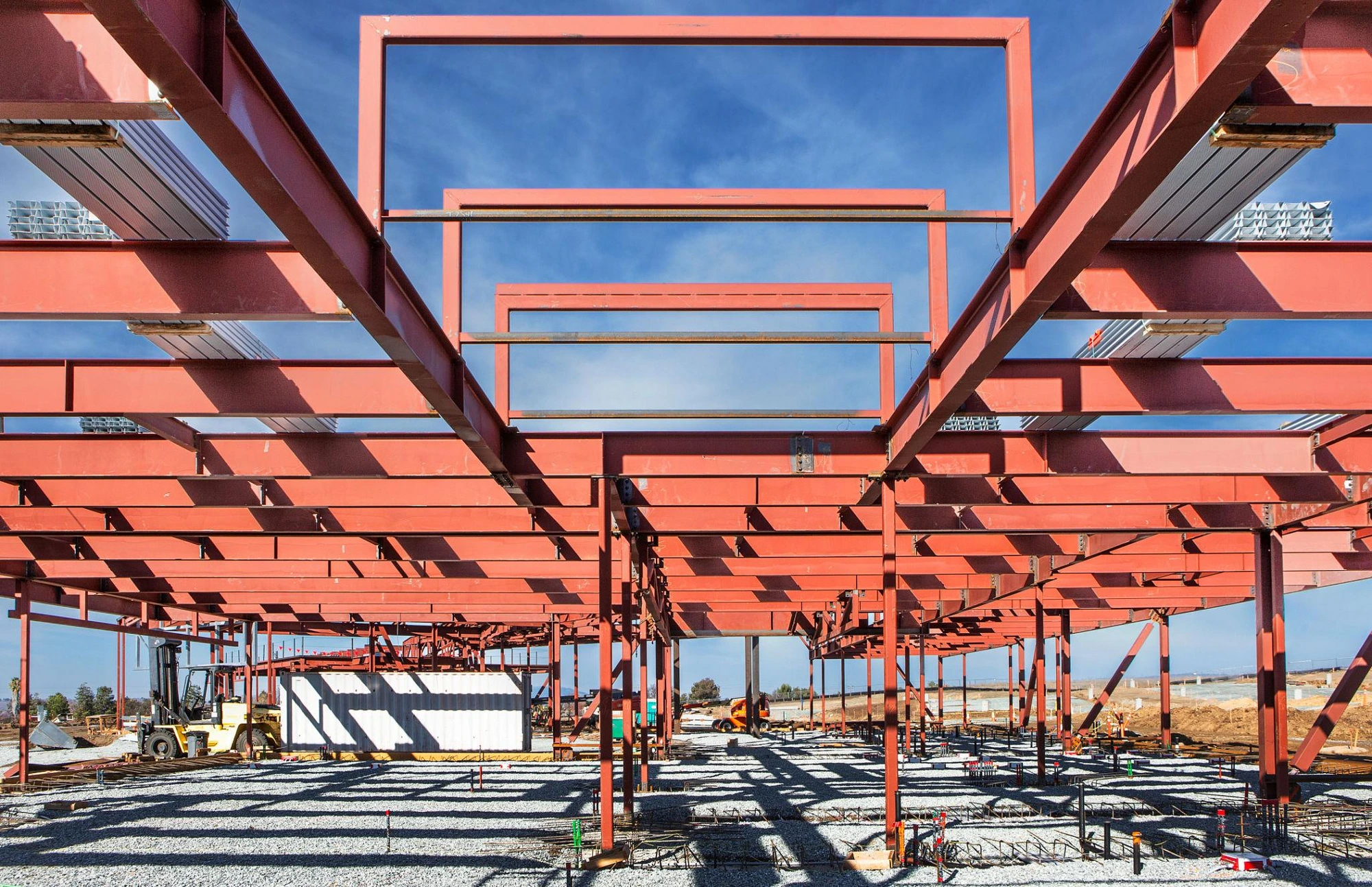 Red steel moment frames rising against a clear sky