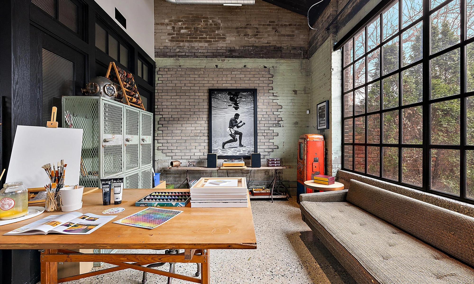 Shop Dog, creative studio with drafting table, Muhammad Ali print, industrial steel windows, sage lockers and vintage gas pump