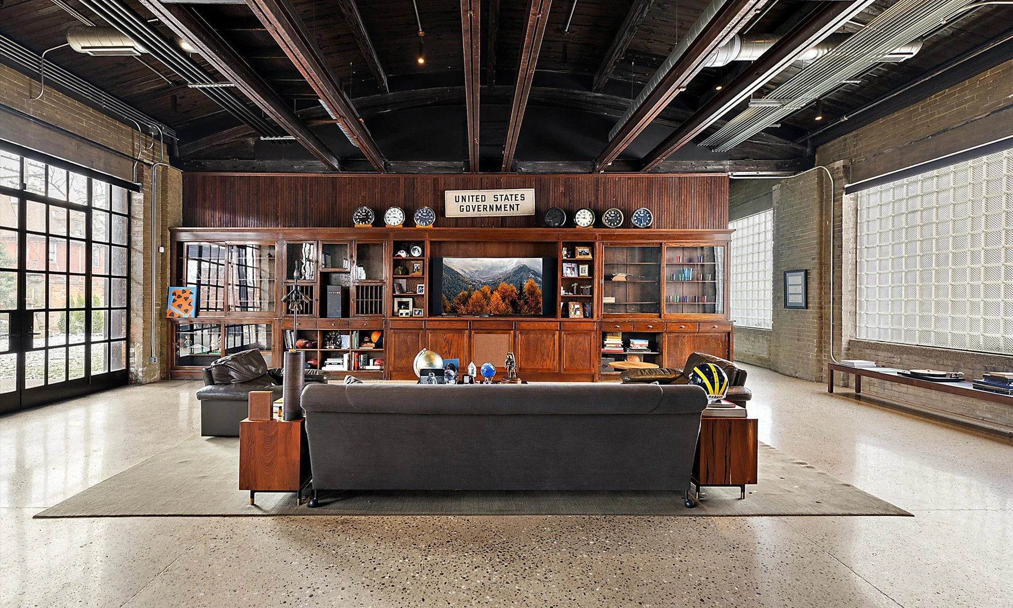 Shop Dog, communal lounge with wall-length walnut cabinetry, sectional, exposed timber beams and glass-block clerestory