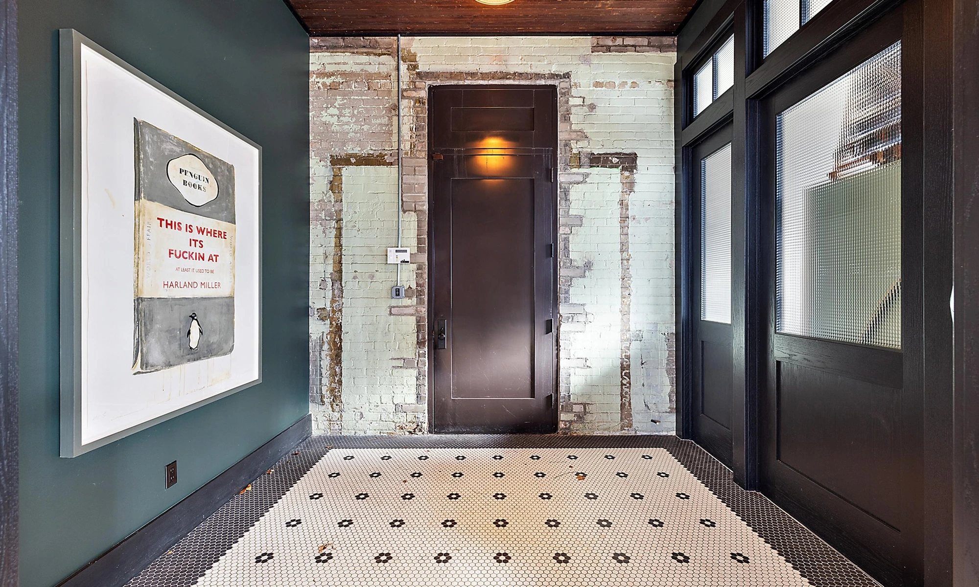Shop Dog, corridor with Harland Miller artwork, distressed painted brick and hexagonal mosaic tile floor under warm sconce light