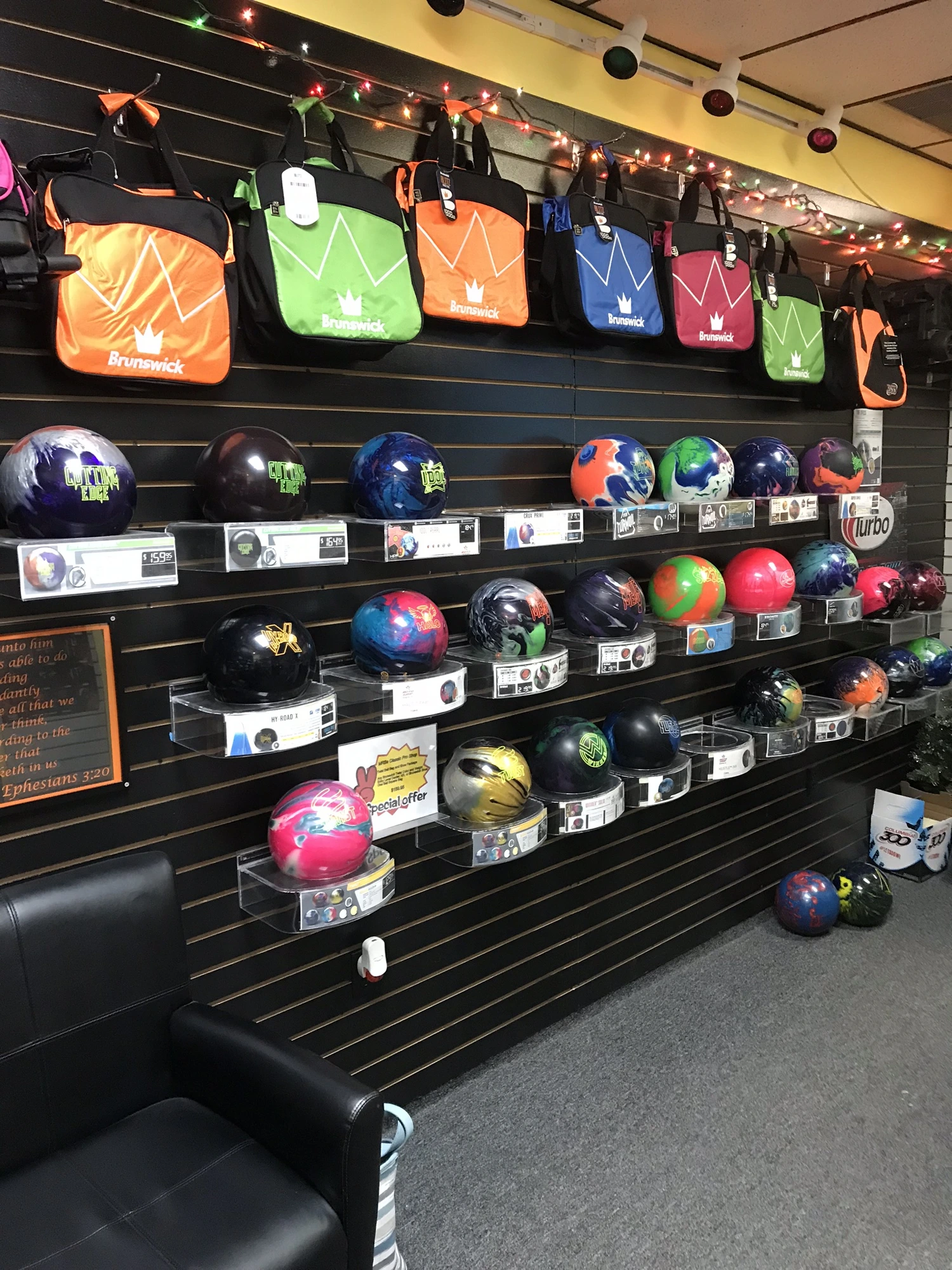 Retail wall with Brunswick bags and a rack of bowling balls